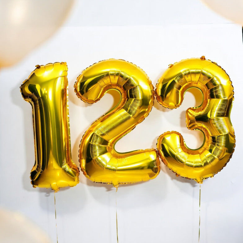 Gold foil balloons shaped like the numbers '123' with white balloons in the background.