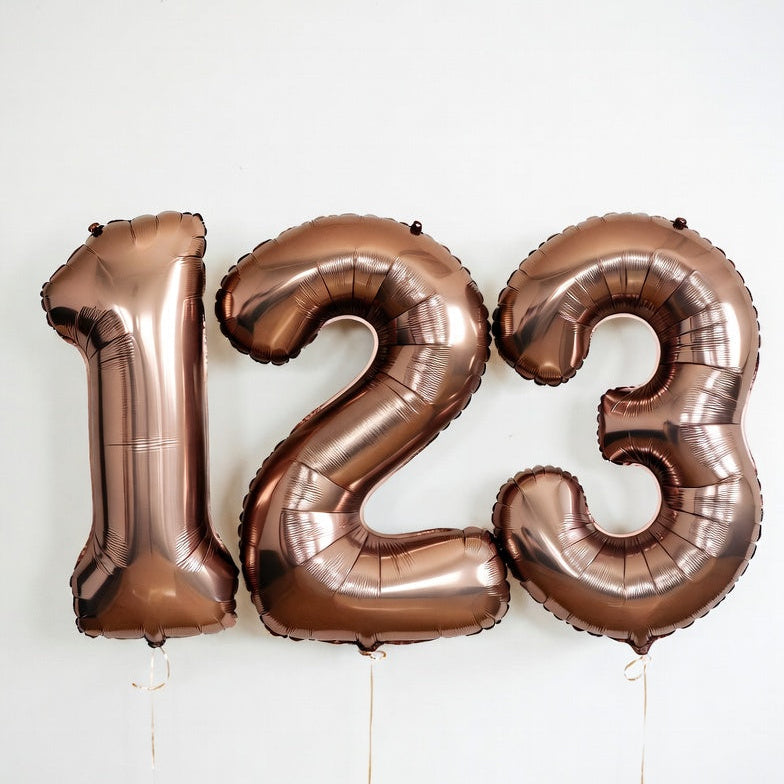 Bronze number balloons spelling '123' on a white background